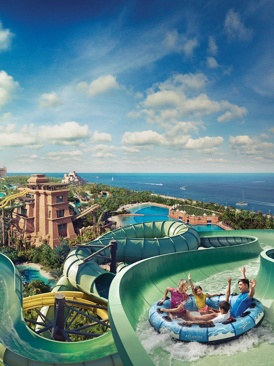 Familie saust im Riesen-Reifen XL-Rutsche hinab, im Hintergrund Dubais Atlantis-Hotel