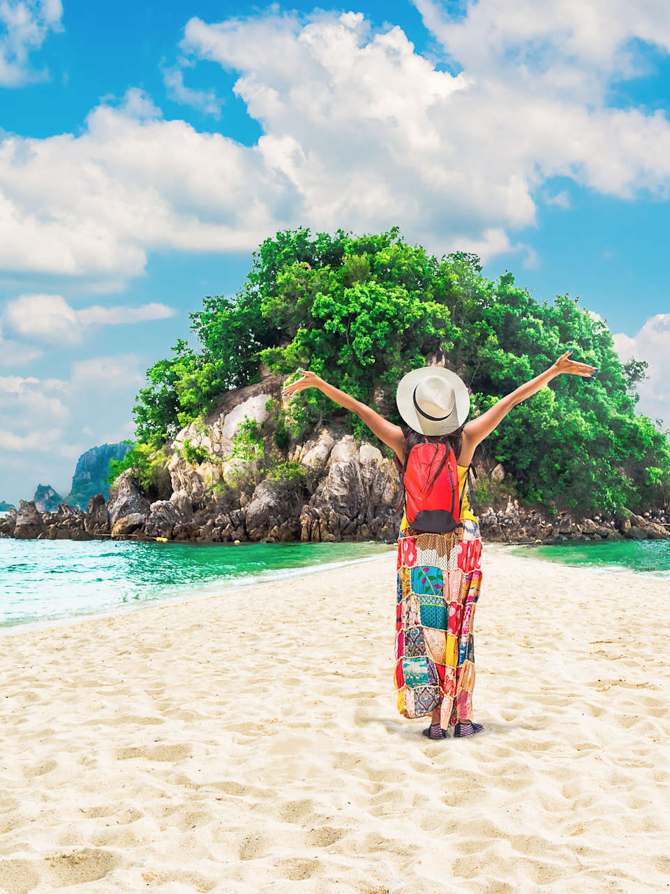 Eine Frau steht mit ausgebreiteten Armein an einem Strand