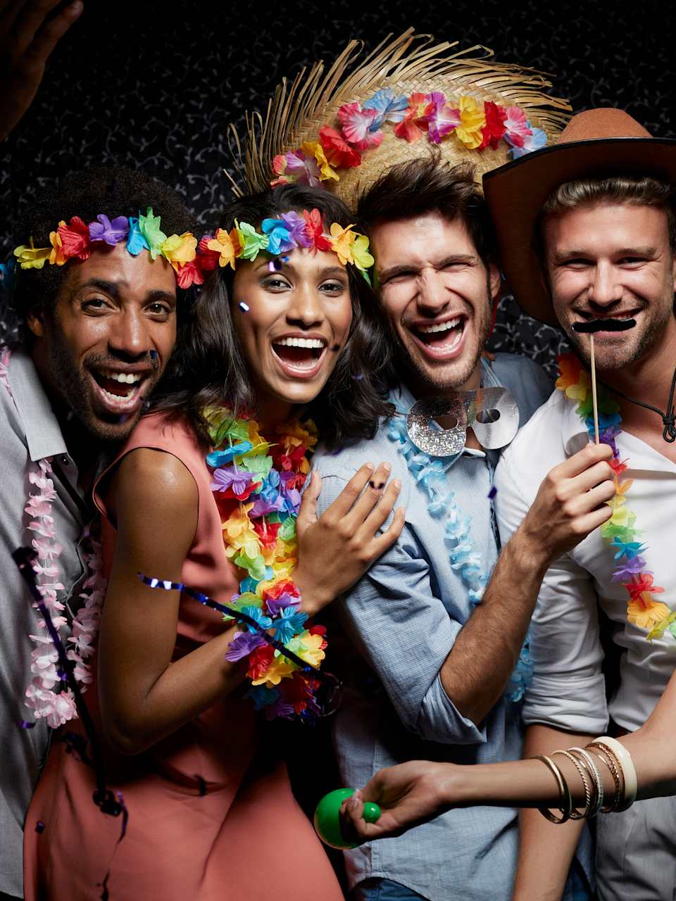Lachende Freunde tragen Girlanden in einem Nachtclub. © Morsa Images/DigitalVision via Getty Images