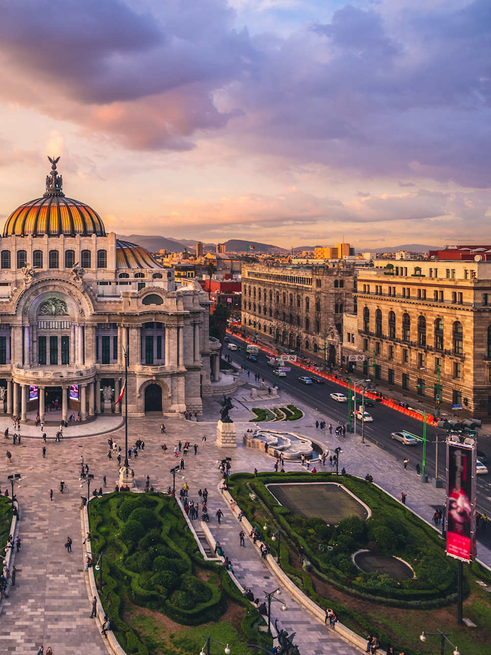 Erhöhte Frontaufnahme eines Museums in Mexiko Stadt. Das Museum hat eine goldene Kuppel und einen mit Säulen gesäumten Eingangsbereich. Vor dem Museum sind vier Grünanlagen zu sehen.