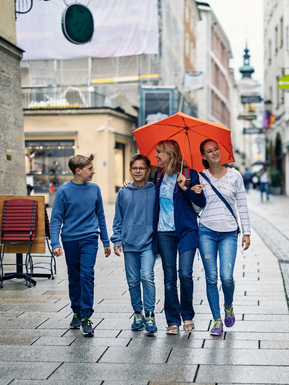 Eine Mutter läuft mit ihren Kindern im Regen durch Salzburg, Österreich. © Imgorthand/E+ via Getty Images