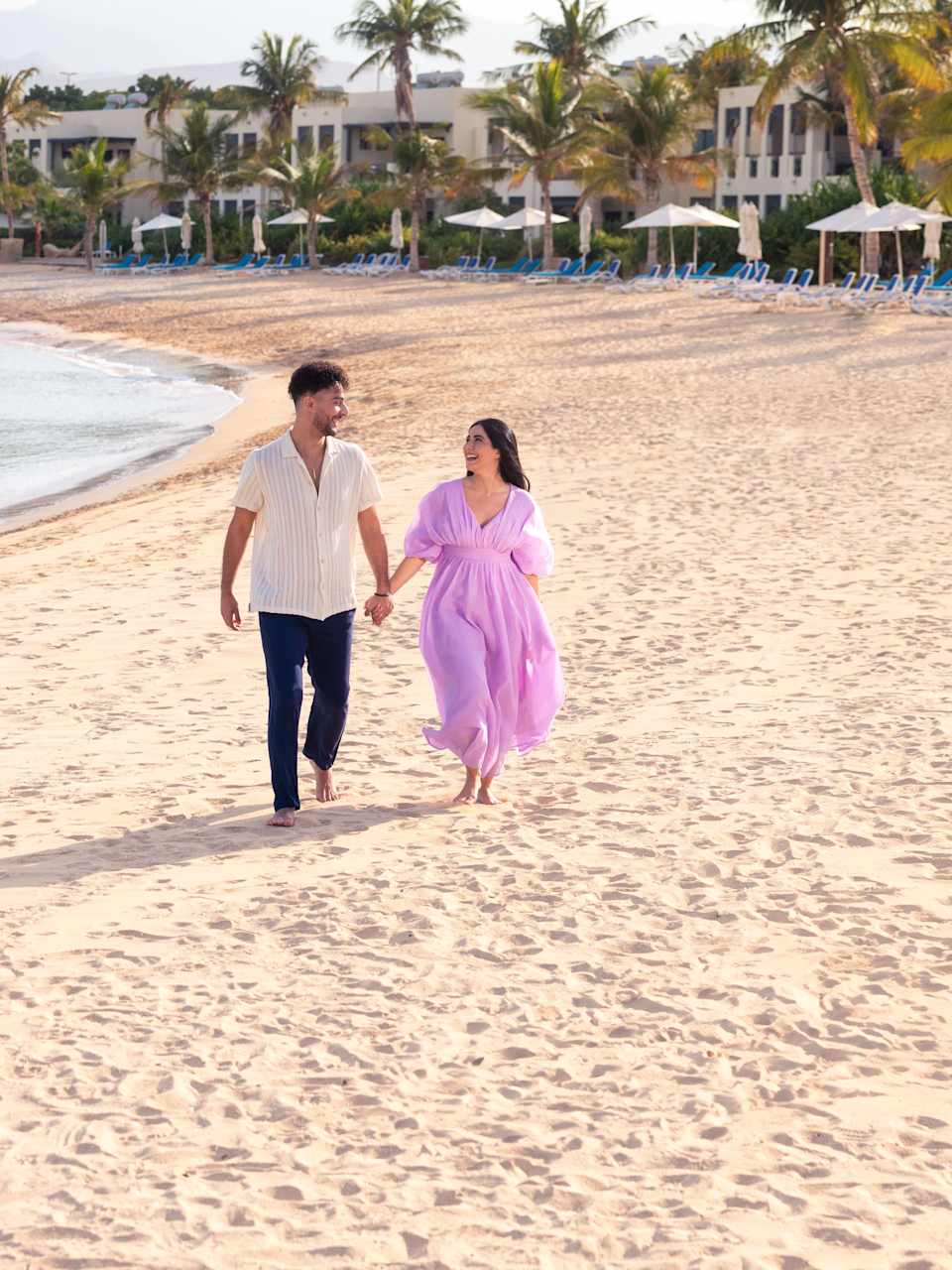 Ein Paar läuft Hand in Hand über einen Strand in Ras Al Khaimah