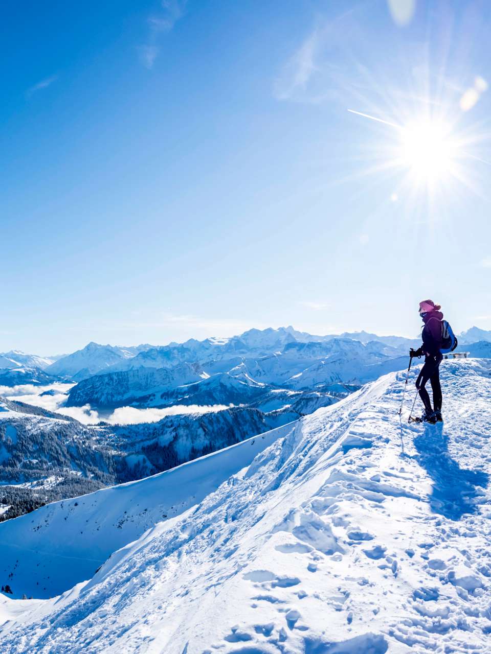 Ein Wanderer steht vor einer Schweizer Fahne auf einem Berg in den Alpen.