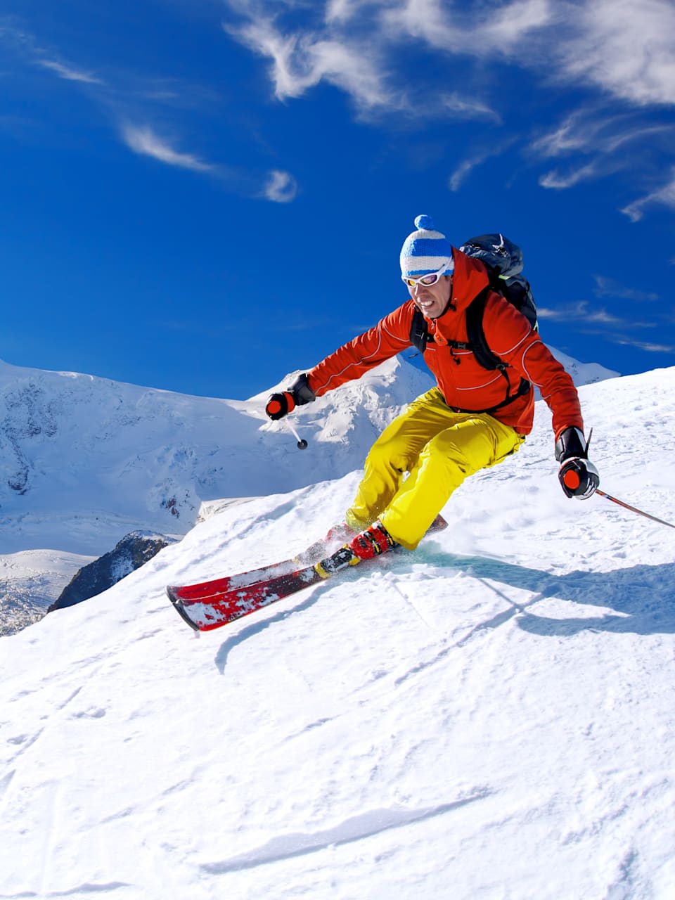 Ein Skifahrer fährt einen verschneiten Berg hinunter.