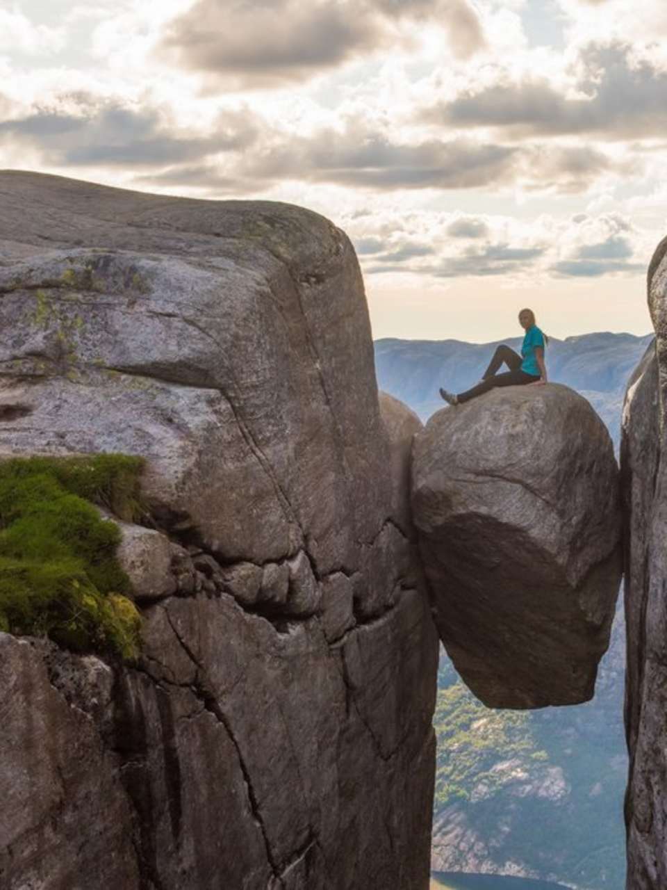 Eine Touristin auf dem norwegischen Kjeragbolten. © iStock via Getty/kotangens