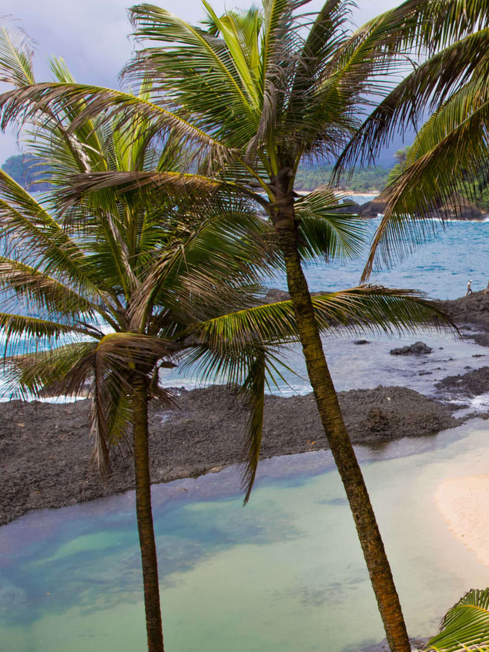 Ein tropischer Strand mit Felsen im Meer auf Sao Tome.