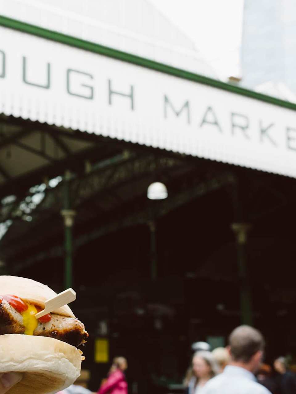 Ein Mann hält ein Sandwich vor dem Borough Market in London.