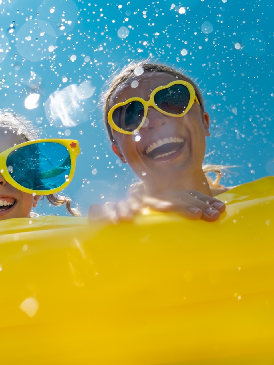 Familie hat Spaß im Wasser, alle tragen gelbe Sonnenbrillen.