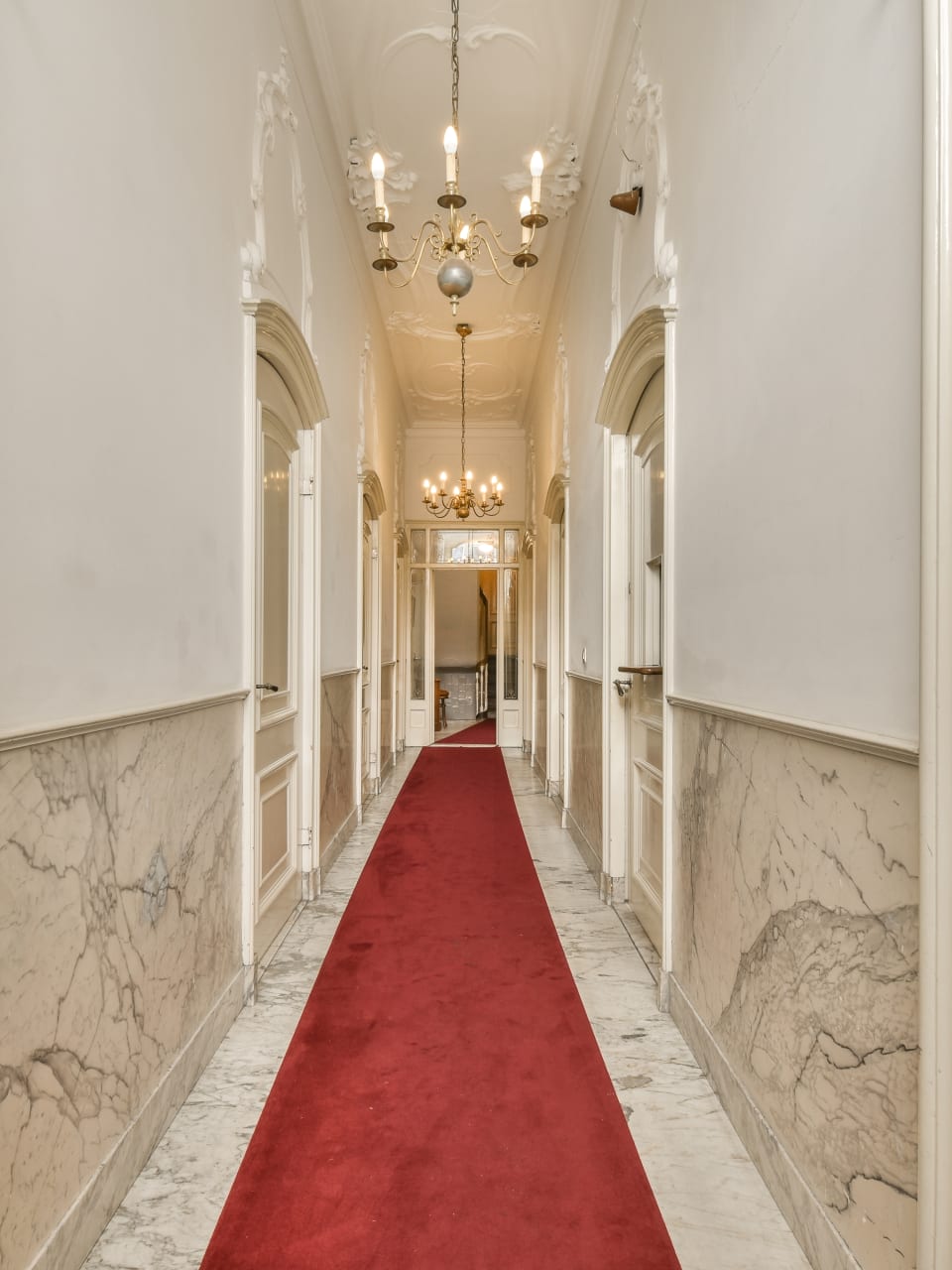 Hotelflur mit rotem Teppich und weißen Wänden