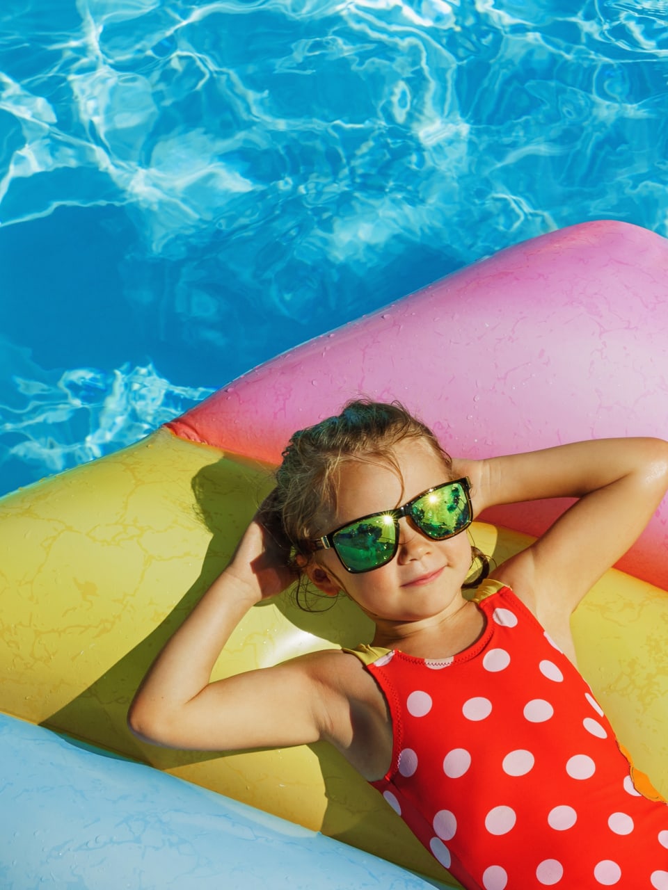 Kind liegt auf Luftmatratze im Pool.