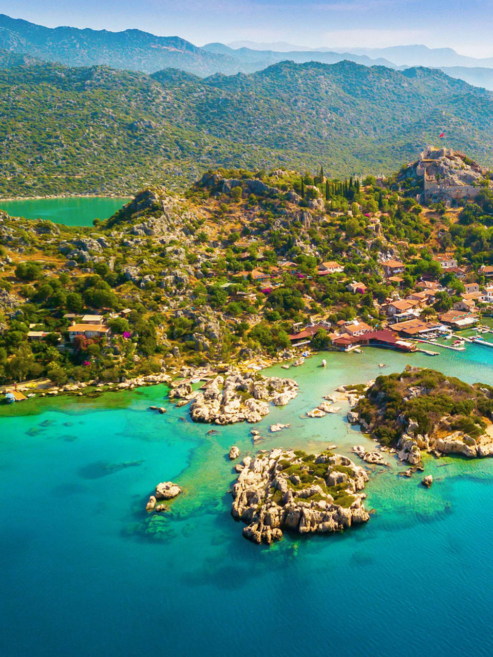Blick auf die Weite der Türkischen Riviera mit grüner Landschaft. Im Vordergrund ist das blaue Meer zu sehen.