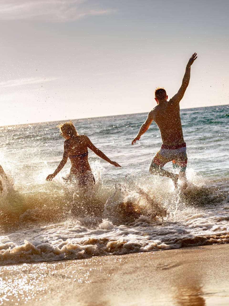 Menschen haben Spaß am Strand und laufen ins Meer.