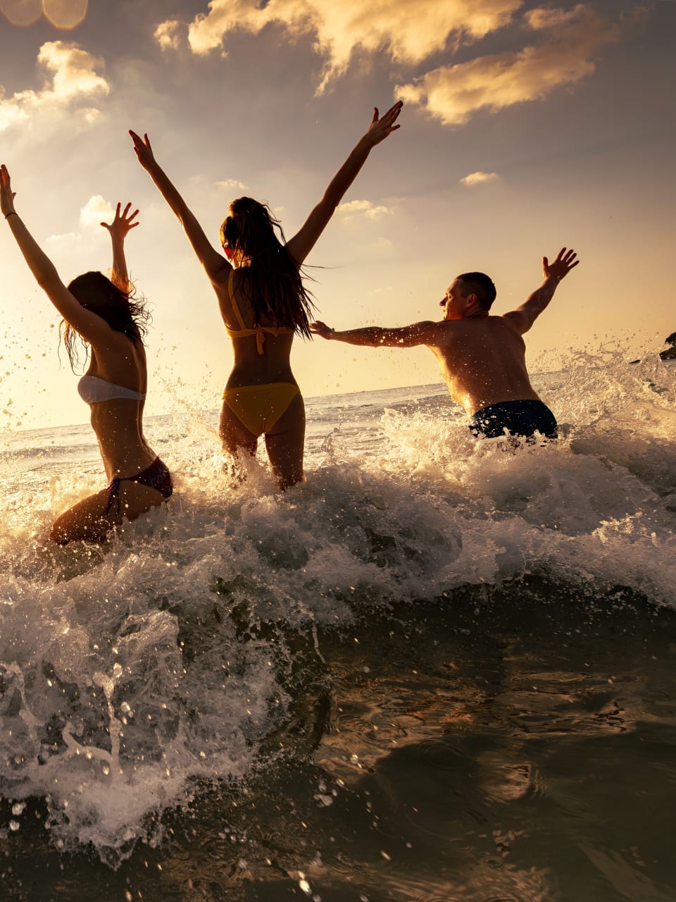 Eine Gruppe Frauen und Männer feiert eine Party am Strand im Meer.