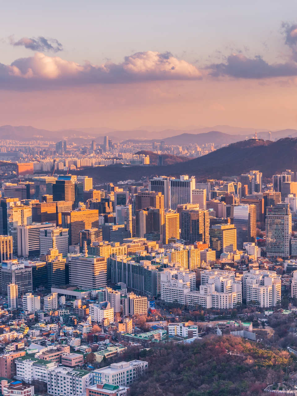 Ein Sonnenuntergang über einer Großstadt mit Bergen im Hintergrund