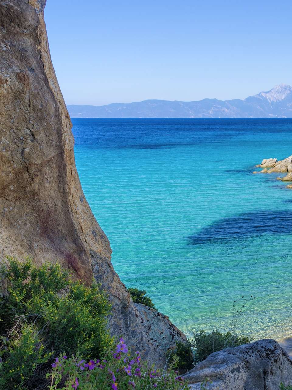 Eine azurblaue Meeresbucht mit klarem Wasser an einem Strand von Sithonia, Chalkidiki, Griechenland
