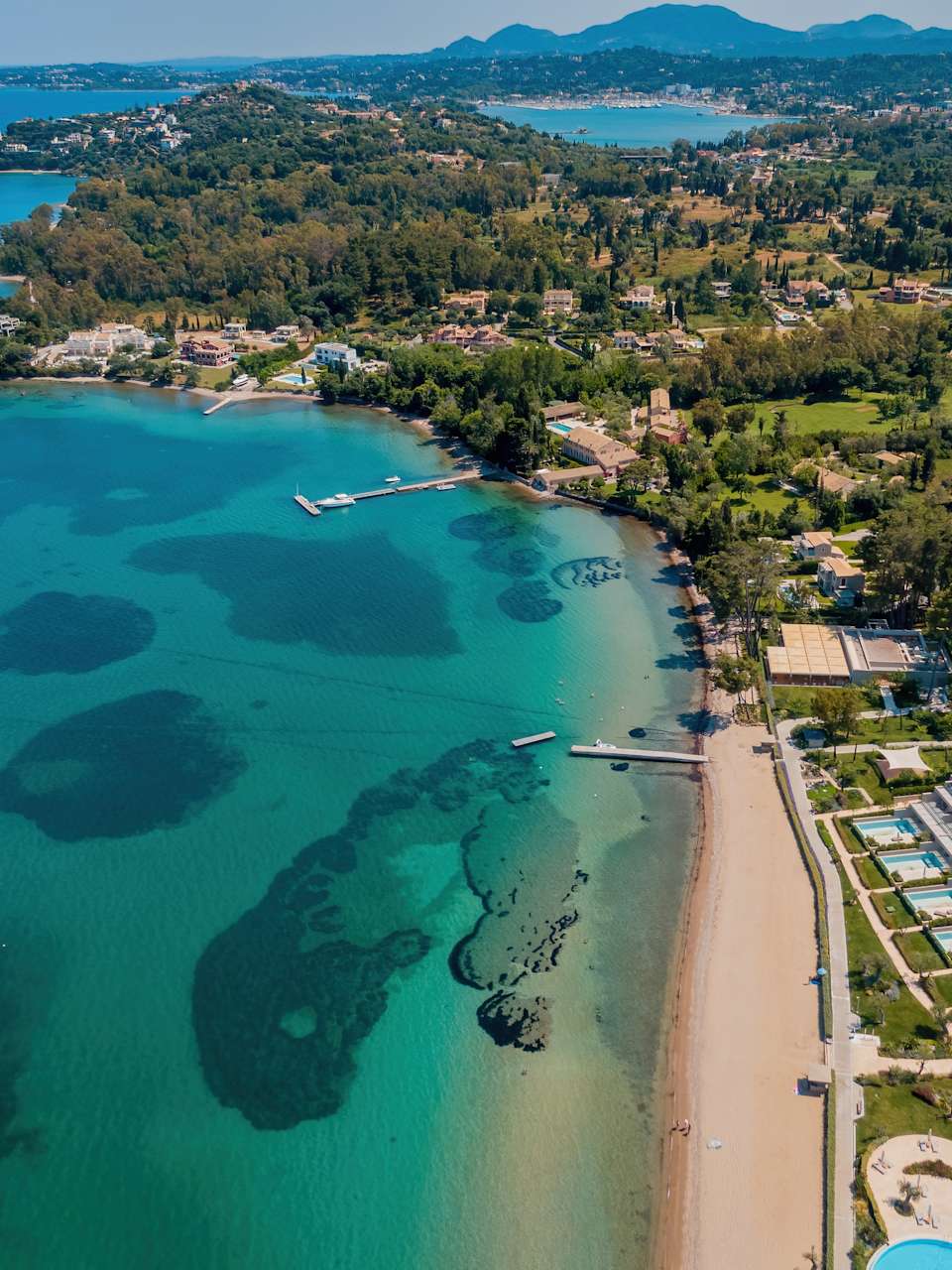 Ein Strand an einer Hotelanlage mit Stegen die ins Wasser führen