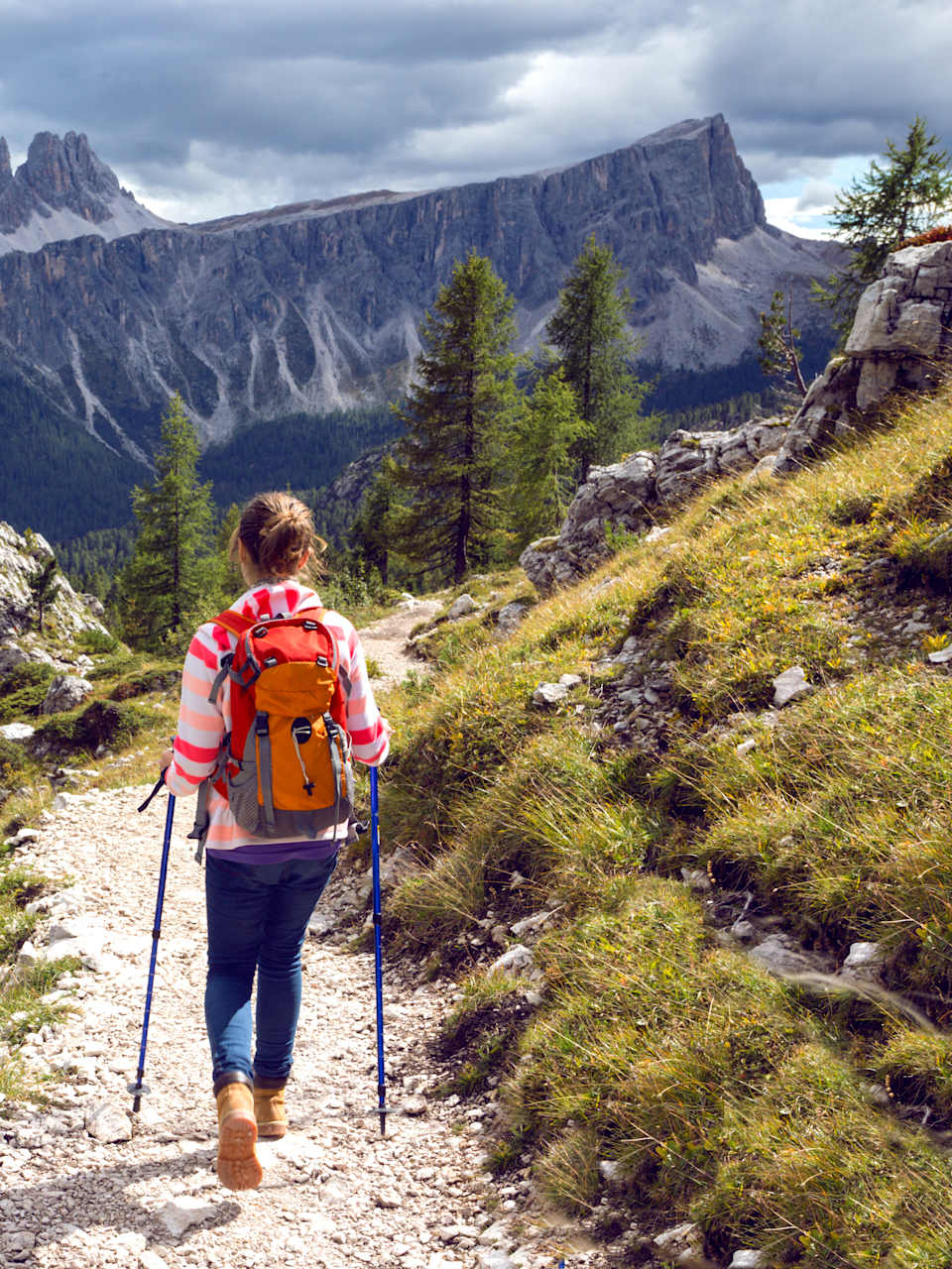 Eine Frau wandert auf einem schmalen Wanderweg vor einer spektakulären Bergkulisse in den Dolomiten in Südtirol, Italien ©shutterstock_1140667871