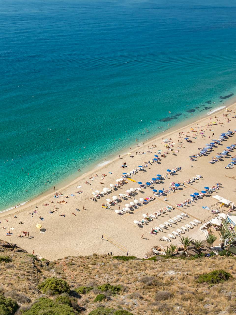EIn Strand mit weißen und blauen Schirmen