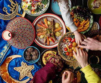 Blick von oben auf eine Vielzahl von Gerichten, mehrere Hände greifen nach Essen