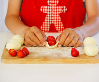 Eine Frau arbeitet Erdbeeren in Knödel ein für die süßen, fruchtigen tschechischen Knödel Ovocné knedlíky.
