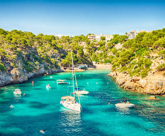 blaues Meer in einer Bucht von Mallorca mit einigen Booten © iStock.com/Josep Bernat Sànchez Moner