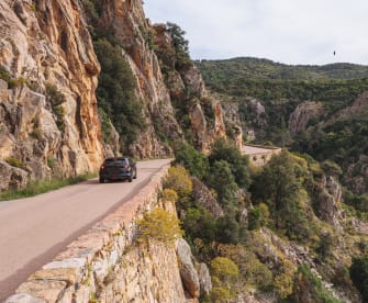 Ein Auto fährt auf einer Straße durch die Berge Korsikas, Frankreich.