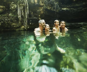 Eine Familie badet in einer Cenote in Mexico.