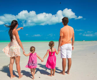 Eine Familie steht an einem Strand und blickt auf das Meer.