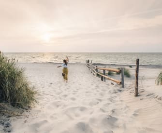Eine Frau rennt einen Strand in Mecklenburg-Vorpommern, Deutschland, entlang. © Francesco Vaninetti Photo/Moment via Getty Images