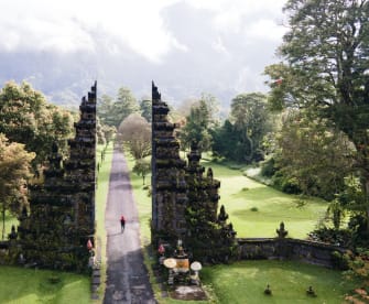 Eine Person läuft durch den Garten eines Tempels auf Bali, Indonesien.