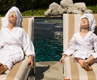 Frau und Kind entspannen mit einer Gurkenmaske im Gesicht am Pool.