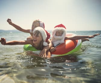 Kinder spielen im Meer auf Schwimmring im Sommer mit Weihnachtsmützen