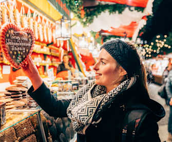 Eine Frau lächelt ein Lebkuchenherz an.