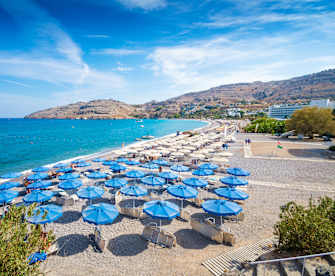 Ein weiter Strand mit blauen Sonnenschirmen
