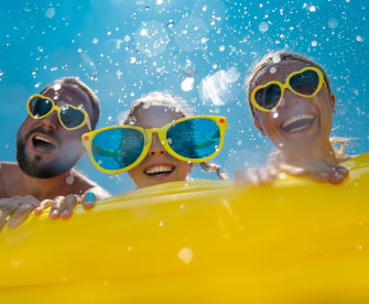 Familie hat Spaß im Wasser, alle tragen gelbe Sonnenbrillen.