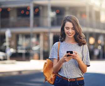 Frau schaut lächelnd auf ihr Smartphone