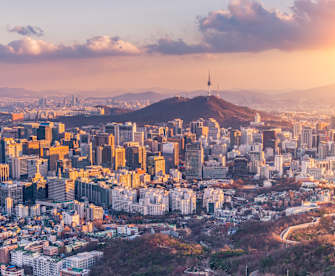 Ein Sonnenuntergang über einer Großstadt mit Bergen im Hintergrund