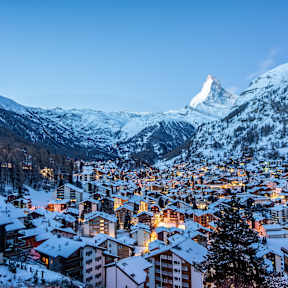 Eine verschneite Stadt in einem Tal mit dem Matterhorn im Hintergrund.