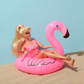 Barbie-Puppe im Badeanzug auf aufblasbarem Flamingo am Strand