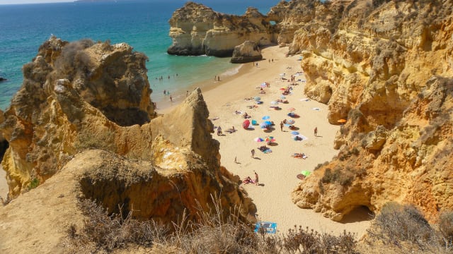 Blick auf einen Strand umgeben von kupferfarbenen Klippen