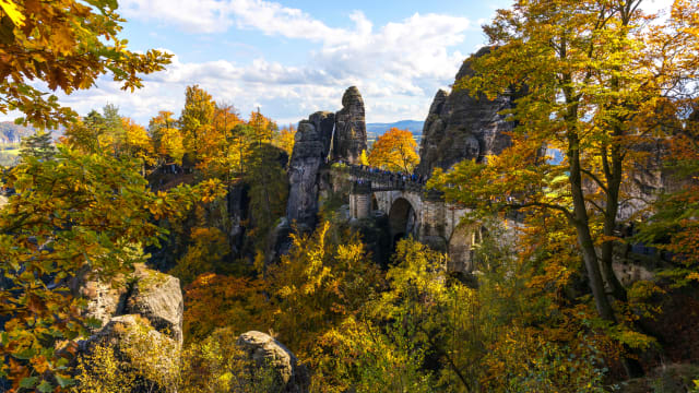Eine Brücke führt durch Felsen umgeben von Bäumen