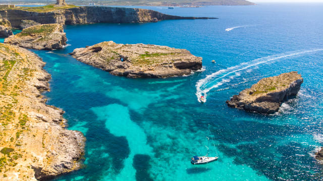 Boote umfahren Felsen im Wasser an der Küste von Comino, Malta.