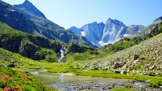 Ein kleiner Bach mit einem Wasserfall und einer Berglandschaft in den Pyrenäen.