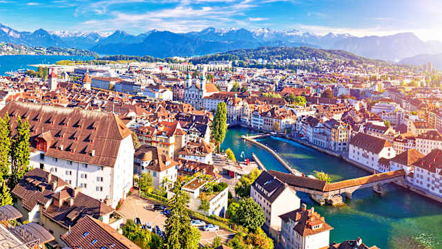 Luftbild einer Stadt mit Fluss und mit Bergen im Hintergrund.