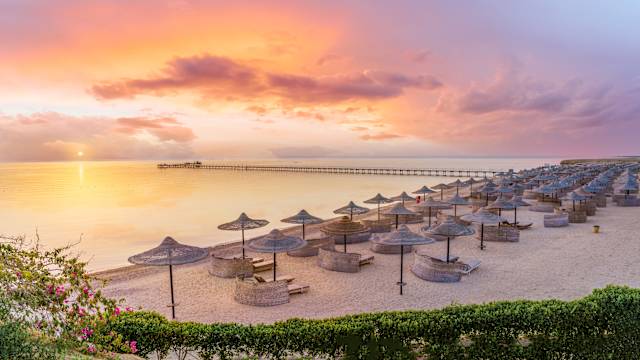 Sonnenuntergang an einem Strand voller Bastschirme.