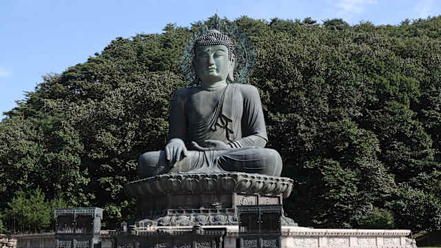 Eine große Buddah-Statue vor Bäumen