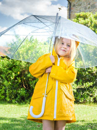 Ein Mädchen mit einem gelben Regenmantel unter einem Regenschirm.