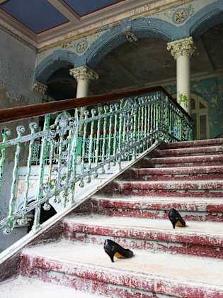 Ein Paar Frauenschuhe auf der Treppe eines heruntergekommenen Hauses.