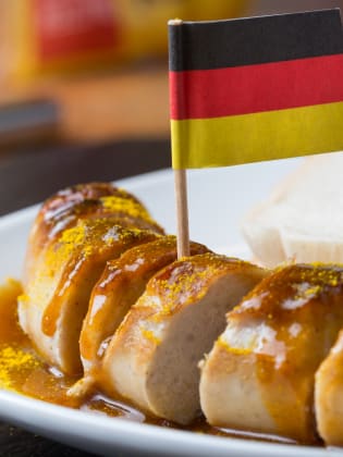 Eine Currywurst mit einer deutschen Flagge. © Teka77/iStock / Getty Images Plus via Getty Images