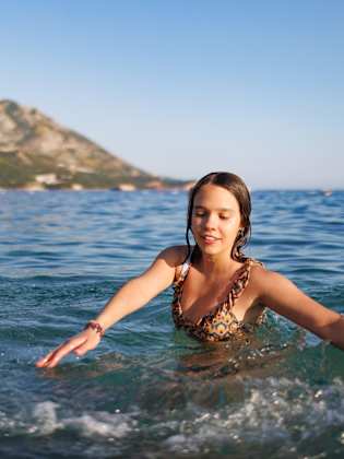 Ein Mädchen im Teenageralter dreht sich im Kreis im Meer © iStock.com/YouraPechkin